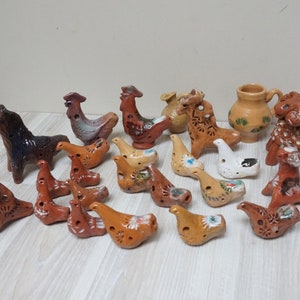 May include: A collection of 18 hand-painted ceramic whistles in the shapes of horses, roosters, and birds. The whistles are decorated with intricate designs and are a traditional folk art.
