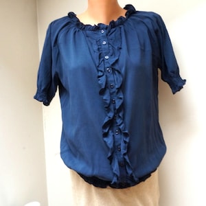 May include: A navy blue blouse with a ruffled front and short sleeves. The blouse has a button closure at the neckline.