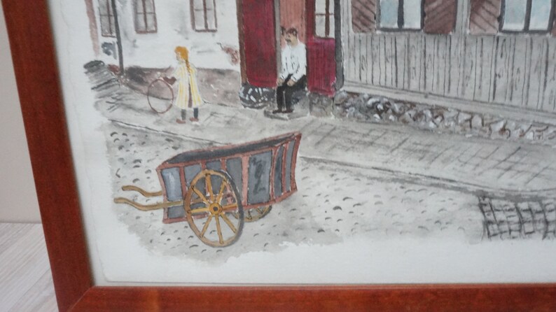 May include: Watercolor painting of a street scene with a child holding a hoop, a man sitting on a porch, and a wooden cart. The artwork is framed in a brown wooden frame. The painting has a vintage aesthetic.