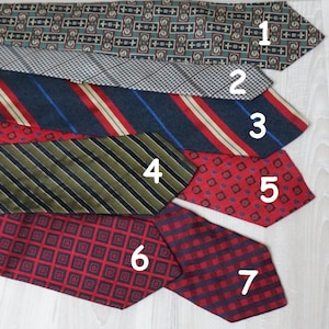 Puede incluir: Siete corbatas de diferentes patrones en varios colores, incluyendo rojo, azul, verde y negro. Las corbatas est&aacute;n dispuestas en una pila, con la corbata superior siendo un patr&oacute;n verde y blanco, y la corbata inferior siendo un patr&oacute;n de cuadros rojos y negros.