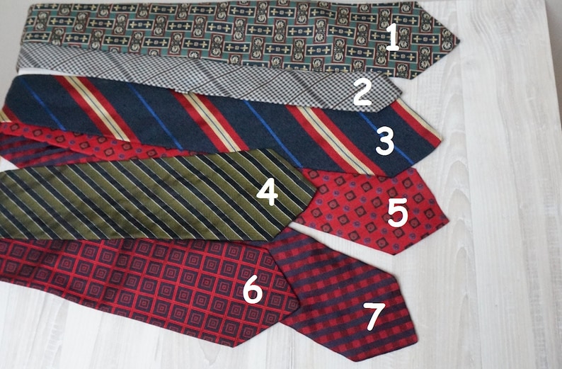 Puede incluir: Siete corbatas de diferentes patrones en varios colores, incluyendo rojo, azul, verde y negro. Las corbatas est&aacute;n dispuestas en una pila, con la corbata superior siendo un patr&oacute;n verde y blanco, y la corbata inferior siendo un patr&oacute;n de cuadros rojos y negros.