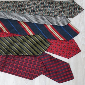 Puede incluir: Una colecci&oacute;n de seis corbatas de seda con patrones en varios colores, incluyendo rojo, azul, verde y negro. Las corbatas est&aacute;n dispuestas en una pila, con la corbata superior siendo una corbata con patr&oacute;n verde y marr&oacute;n.