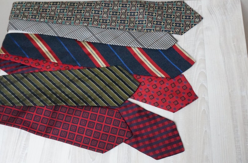 Puede incluir: Una colecci&oacute;n de seis corbatas de seda con patrones en varios colores, incluyendo rojo, azul, verde y negro. Las corbatas est&aacute;n dispuestas en una pila, con la corbata superior siendo una corbata con patr&oacute;n verde y marr&oacute;n.