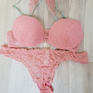 Könnte beinhalten: Ein rosafarbenes Spitzen-BH- und Höschen-Set mit einem hellgrünen Spitzendetail an den BH-Trägern.