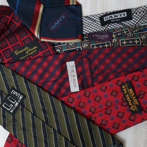 Puede incluir: Una colecci&oacute;n de corbatas de seda en varios patrones y colores, incluyendo rojo, verde, azul y negro. Las corbatas presentan diferentes marcas, incluyendo "GANT", "TIE RACK", "JOTUN" y "LOE HAUGE SIND".