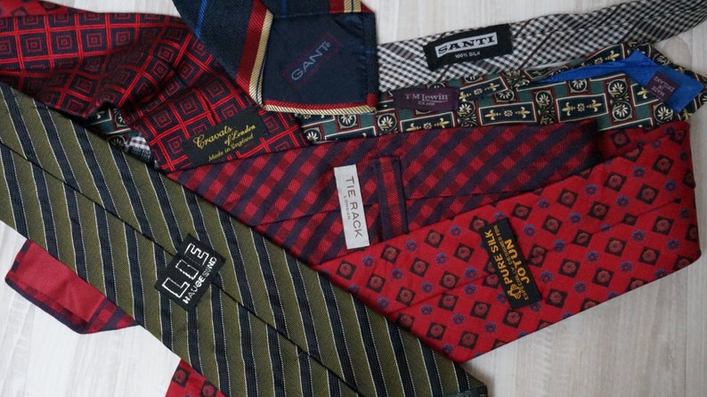 Puede incluir: Una colecci&oacute;n de corbatas de seda en varios patrones y colores, incluyendo rojo, verde, azul y negro. Las corbatas presentan diferentes marcas, incluyendo "GANT", "TIE RACK", "JOTUN" y "LOE HAUGE SIND".