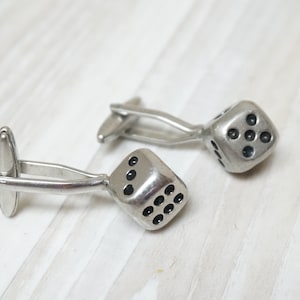 May include: A pair of silver cufflinks with black dice designs.