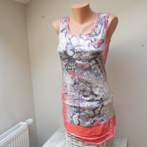 Peut inclure: Une robe sans manches avec un imprimé abstrait gris et rose. La robe a une bordure à volants.