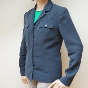 May include: A dark blue blazer with a single button closure and a flap pocket on the left side.