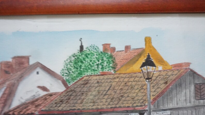 May include: Watercolor painting of a European town scene. The artwork depicts buildings with red tile roofs, a yellow building, and a street lamp. A green tree and a light blue sky are also visible.