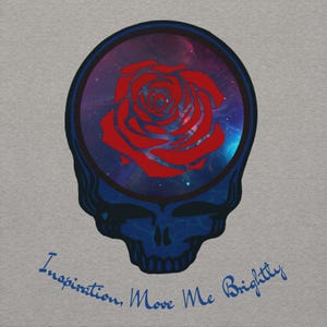 May include: A gray t-shirt featuring a blue skull design with a red rose inside a circular frame. The background within the frame shows a galaxy. The text "Inspiration, Move Me Brightly" is written in blue script below the skull.