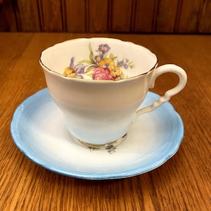 Taza de té y platillo Royal Stafford en azul huevo de petirrojo, ramo floral de rosas e iris, taza y platillo con pie