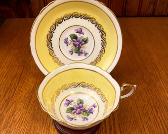 Vintage Paragon amarillo con remolinos dorados y violetas púrpuras, taza de té y platillo