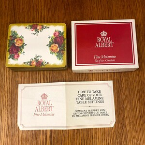 May include: A set of six Royal Albert fine melamine coasters with a floral design. The coasters are packaged in a red box with the Royal Albert logo and the text "Fine Melamine Set of six Coasters".
