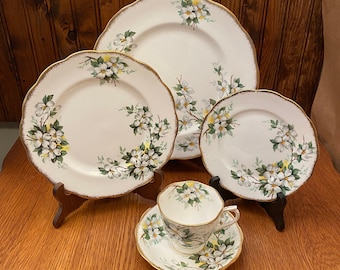 May include: A set of white floral china with gold trim, including a teacup, saucer, and three plates of varying sizes.