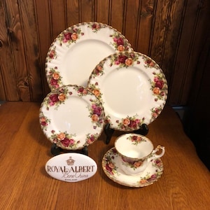 Puede incluir: Un juego de vajilla de porcelana fina Royal Albert Old Country Roses, que incluye una taza de té y un platillo, un plato para pan y mantequilla, un plato para ensalada y un plato para cenar. Los platos presentan un diseño floral con rosas, hojas y bordes dorados.