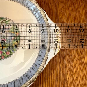Pu&ograve; includere: Un piatto in ceramica bianca con un motivo floreale blu e oro. Il piatto ha un diametro di 25,4 cm.