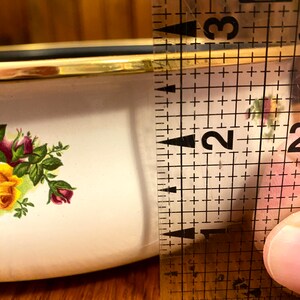 May include: A white ceramic bowl with a gold rim and a floral pattern. The bowl is 2 inches in diameter.