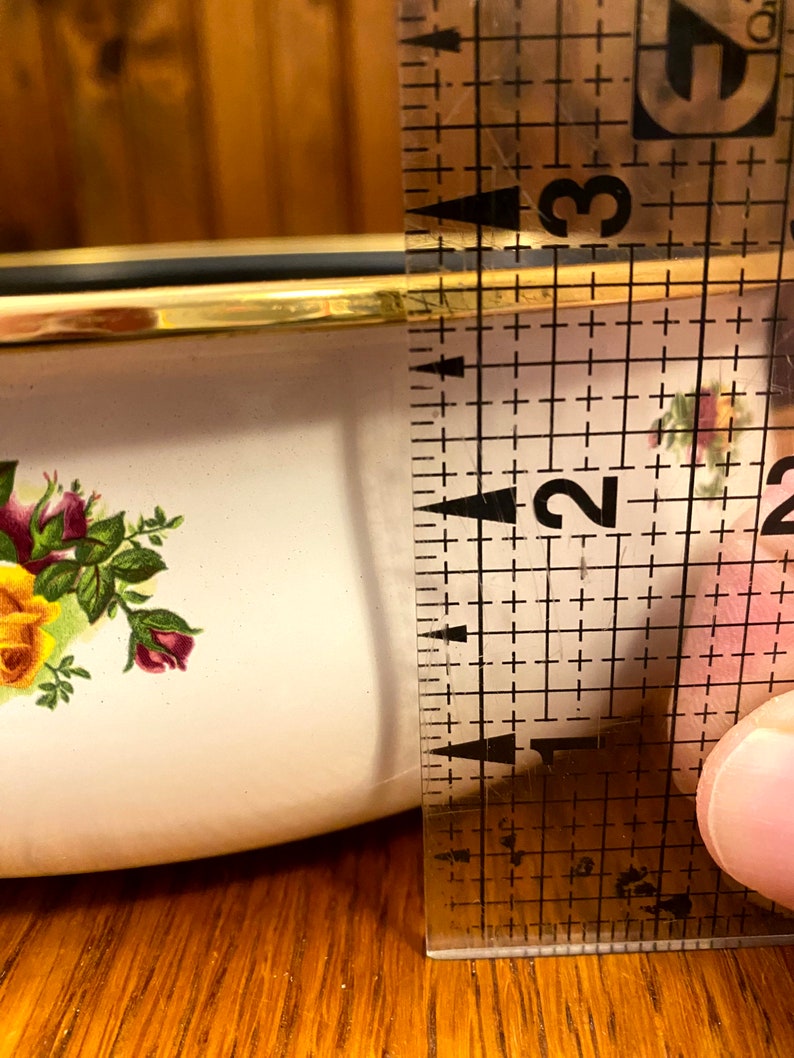 May include: A white ceramic bowl with a gold rim and a floral pattern. The bowl is 2 inches in diameter.