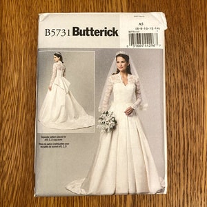 Op de afbeelding: Een bruidsjurkpatroon van Butterick, patroonnummer B5731, maat A5 (6-8-10-12-14). Het patroon bevat aparte stukken voor AB, C, D cupmaten. De afbeelding toont een witte bruidsjurk met een kantbovenstuk en lange mouwen. De jurk heeft een volle rok en een sleep.