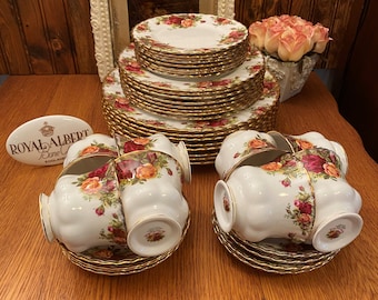 May include: A set of Royal Albert Old Country Roses fine bone china teacups and saucers. The set includes a stack of plates with a gold trim and a floral pattern.