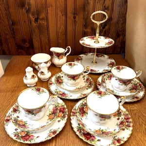 Puede incluir: Un juego de tazas de té y platillos vintage con un patrón floral. El juego incluye una tetera, una jarra de crema, un azucarero y un soporte de servicio de dos niveles.