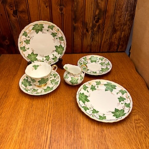 Könnte beinhalten: Ein Vintage-Teeservice mit einem grünen Efeu-Muster. Das Set enthält eine Teekanne, eine Milchkännchen, eine Teetasse und eine Untertasse.