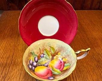 Taza y platillo de té color burdeos, de la marca Vintage Aynsley, firmados por el artista D Jones, con diseño de frutas de huerto.