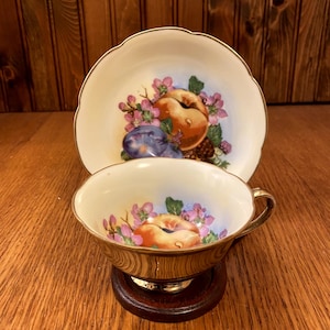 Taza de té y platillo con frutas y bayas pintadas a mano, hecho en Japón, con exterior dorado brillante.