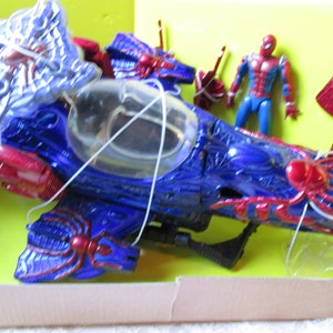 May include: A blue and red toy spider-themed motorcycle with a clear cockpit and a red spider figure on the side. A red and blue action figure of Spider-Man is included.