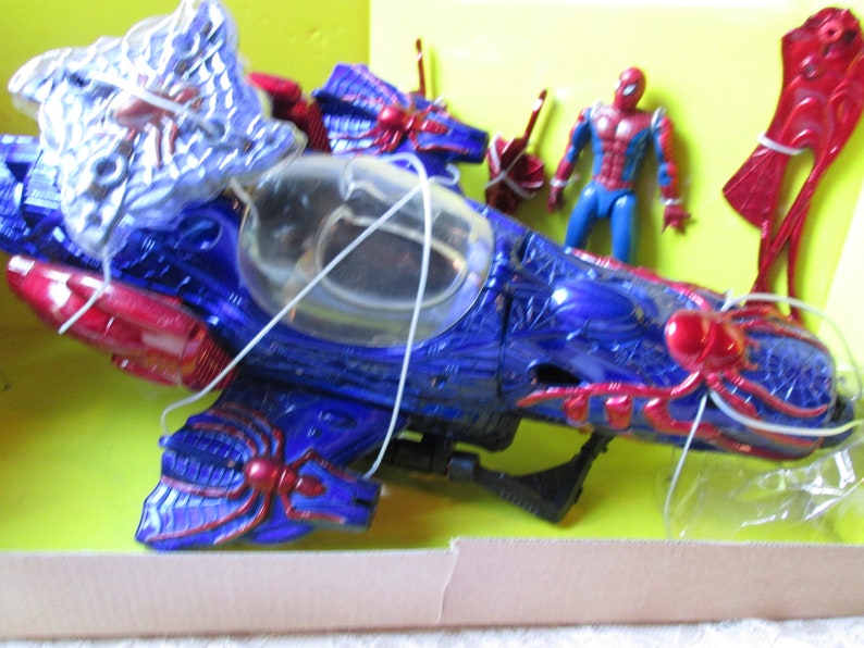 May include: A blue and red toy spider-themed motorcycle with a clear cockpit and a red spider figure on the side. A red and blue action figure of Spider-Man is included.