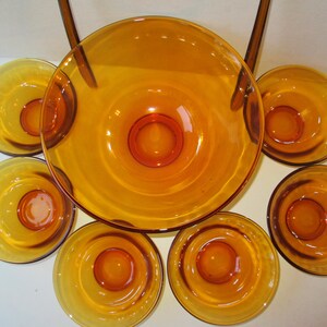 Peut inclure: Service de table en verre ambr&eacute;, comprenant un grand saladier et six petits bols. Les bols ont un design circulaire avec un centre sur&eacute;lev&eacute;. L'ensemble est id&eacute;al pour servir des collations ou des desserts.