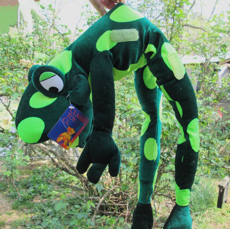 Pu&ograve; includere: Marionetta di rana di peluche verde con grandi occhi verdi e macchie verde lime. La marionetta &egrave; piegata con le braccia distese. La marionetta ha un'etichetta che recita "Classic Toy Co."