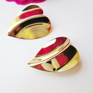May include: A pair of gold-tone heart-shaped earrings with a wavy design.