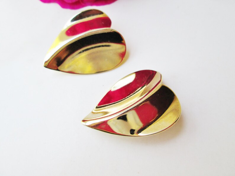 May include: A pair of gold-tone heart-shaped earrings with a wavy design.