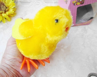May include: A yellow plush chick toy with orange feet and a yellow wing. The chick is wound up and will walk when released.