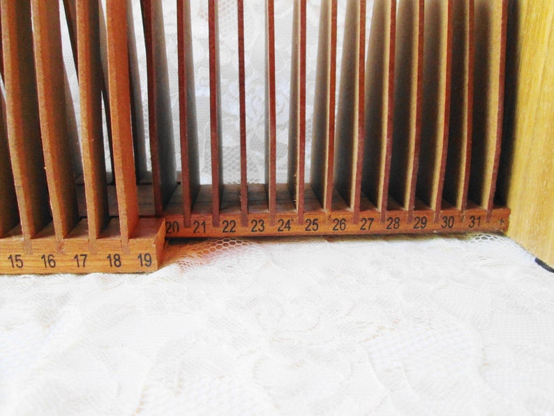 May include: Wooden storage unit with 31 numbered slots for organizing items. The slots are labeled with numbers from 15 to 31.