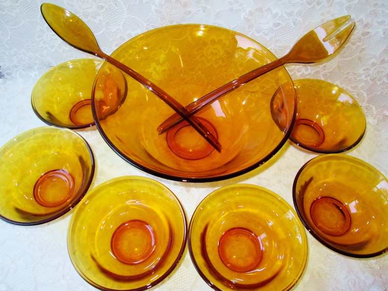 Peut inclure: Un ensemble de saladiers vintage en verre ambr&eacute;. L'ensemble comprend un grand saladier, six petits bols et deux cuill&egrave;res &agrave; salade. Les bols et les cuill&egrave;res ont une teinte jaune-dor&eacute;, id&eacute;ale pour servir des salades.