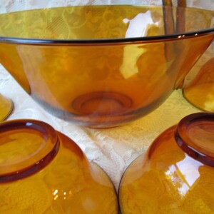 Peut inclure: Un ensemble de bols en verre ambr&eacute;. L'ensemble comprend un grand saladier et plusieurs petits bols. Les bols ont une finition lisse et brillante et un bord marron fonc&eacute;. Les bols sont probablement destin&eacute;s &agrave; servir des aliments.