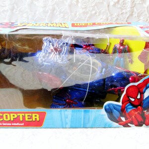 May include: A blue and red toy helicopter with a spider web design. The helicopter has a red and blue spider figure on the front and a red and blue spider figure on the back. The helicopter is in a plastic package with a red and blue Spider-Man figure on the front. The package says "Web Copter" and "Con ca&ntilde;on lanza micilcol".