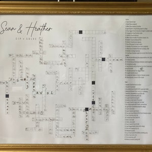 May include: A black and white crossword puzzle with the title "Sean & Heather Sip + Solve". The puzzle is framed in a gold frame.