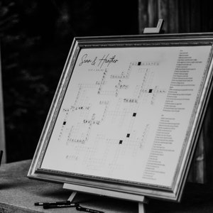May include: A black and white photo of a wedding sign with a crossword puzzle. The sign says "Sean & Heather" at the top and has a list of clues for the crossword puzzle on the right side.