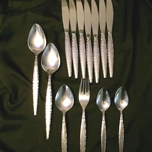May include: A set of silverware with a decorative pattern on the handles. The set includes knives, forks, and spoons.