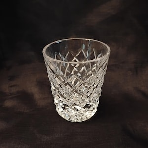 May include: A white ceramic mug with a black handle and the text "But First, Coffee" in a bold, black font. The mug is set against a blurred background, suggesting a cozy setting. The mug appears to be approximately 4 inches tall.