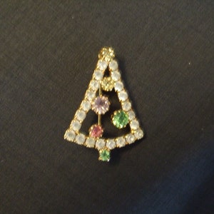 May include: A gold-tone Christmas tree brooch with clear, pink, and green rhinestones.