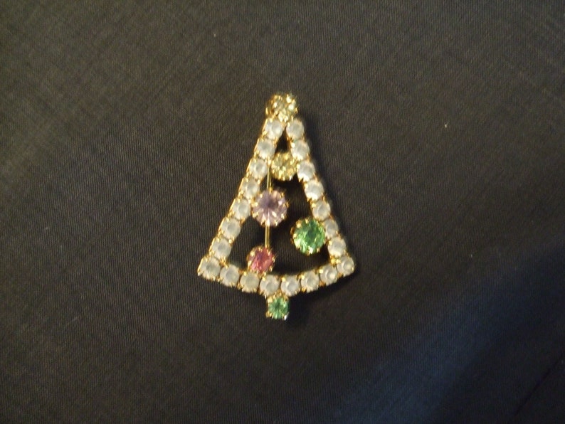 May include: A gold-tone Christmas tree brooch with clear, pink, and green rhinestones.