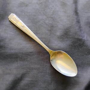 May include: A silver spoon with an ornate design on the handle. The handle is engraved with the text "Oneida Community Ltd. 1947."