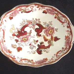 May include: An oval serving dish with two handles. The dish is white with a red and gold floral pattern.