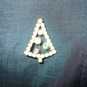 May include: A gold-tone Christmas tree brooch with clear, pink, and green rhinestones.