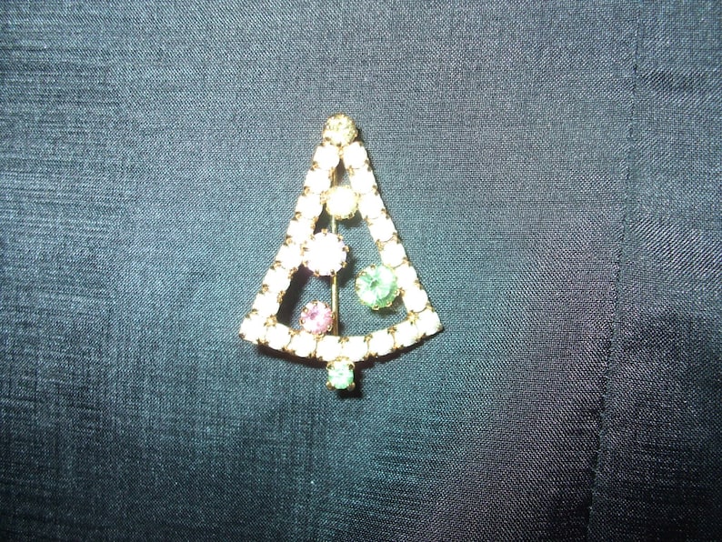 May include: A gold-tone Christmas tree brooch with clear, pink, and green rhinestones.